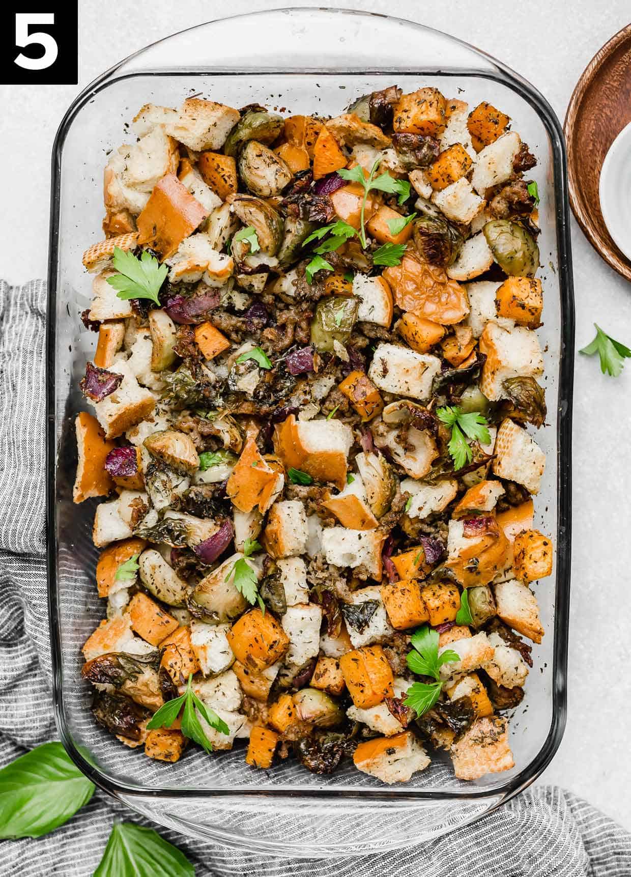 Overhead photo of Autumn Roasted Vegetable Stuffing recipe in a glass casserole dish on a white background.