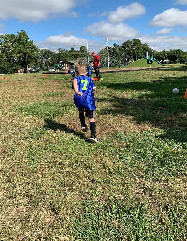 A boy in a soccer jersey running.