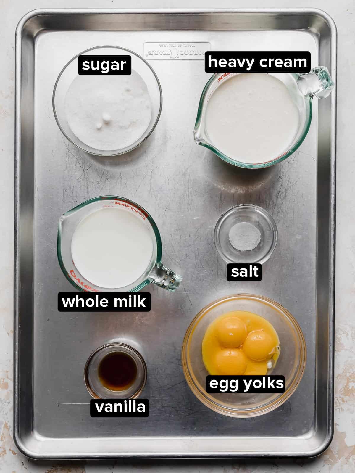 Homemade Vanilla Ice Cream ingredients portioned into glass bowls, on a silver baking sheet.