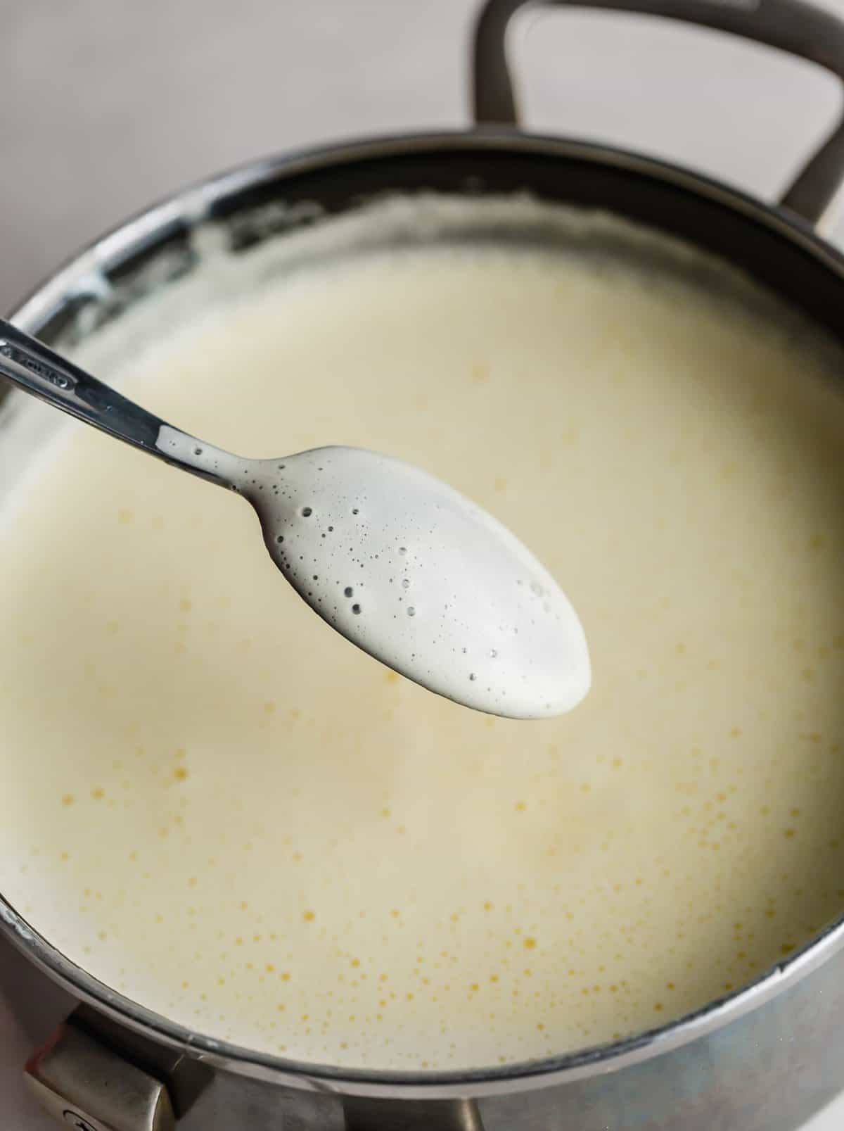 A light yellow vanilla ice cream mixture coating the back of a spoon.