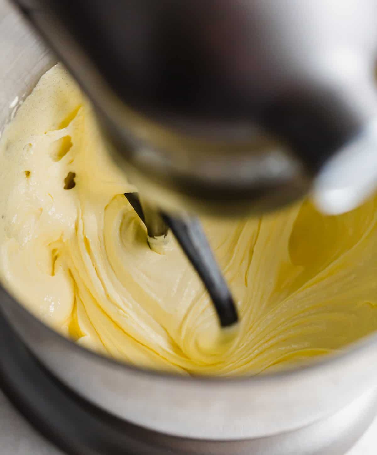 A light yellow fluffy mixture being mixed by a stand mixer.