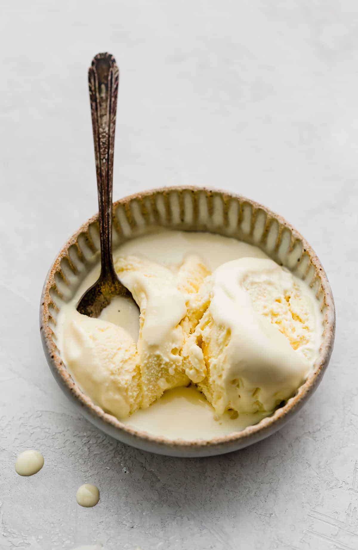 Homemade vanilla ice cream ball in spoon on ice cream container on