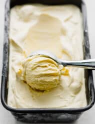 Homemade Vanilla Ice Cream in a bread pan with an ice cream scoop scooping out a ball of ice cream.