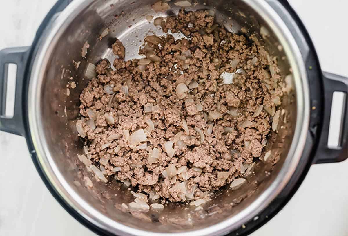 Ground beef and diced onions in an instant pot.