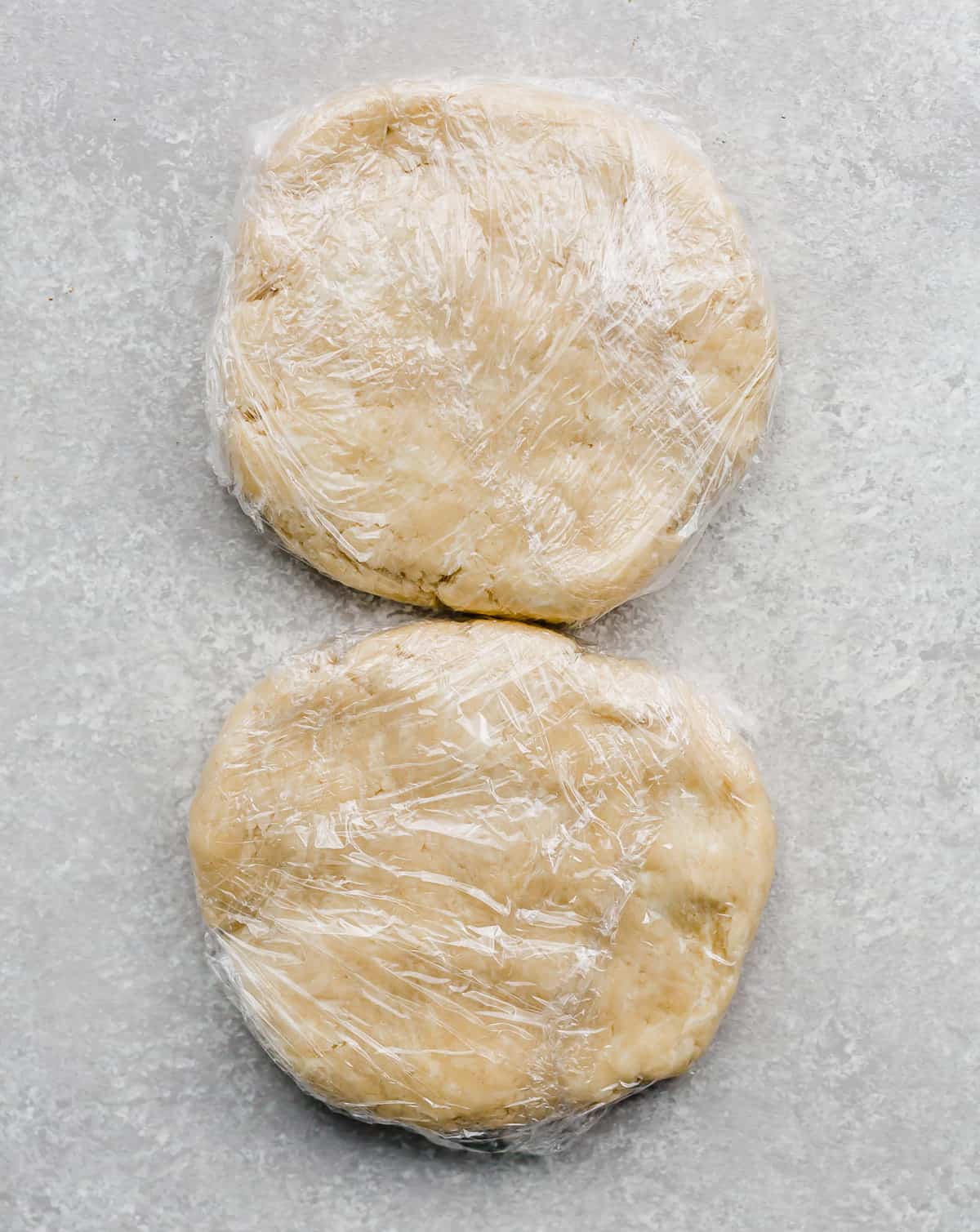 Two pie crust dough disks on a gray background.