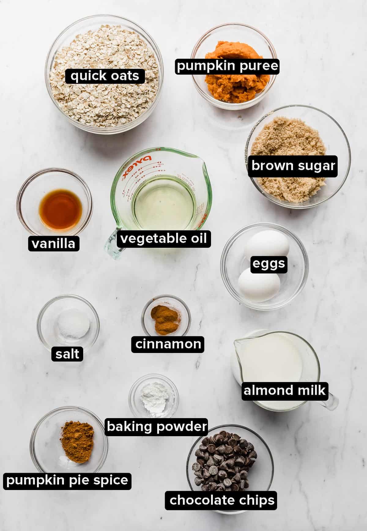 Pumpkin Baked Oatmeal Cups ingredients in glass bowls on a white background.