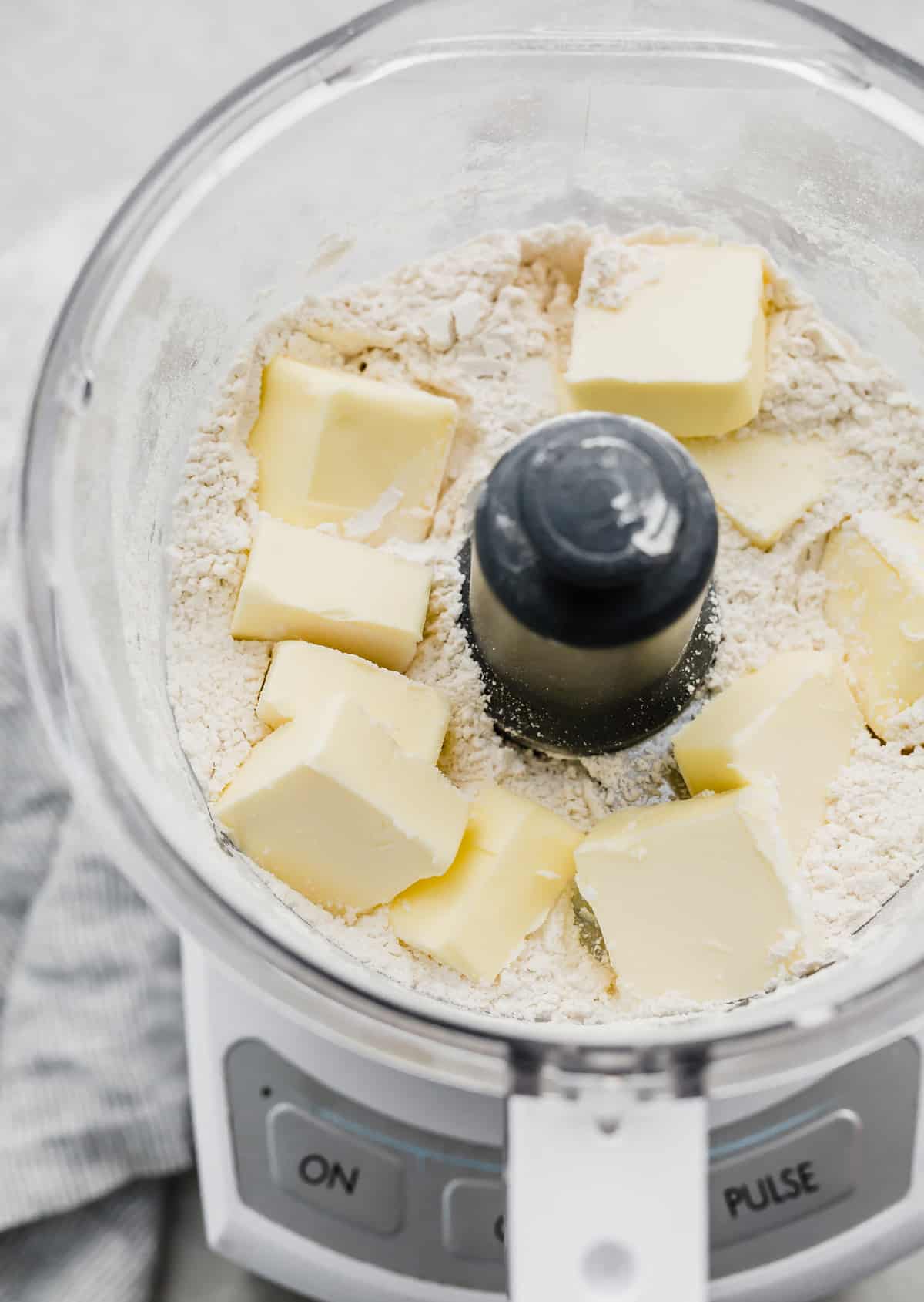 A food processor with flour and cubed butter in it, for making a Food Processor Pie Crust.
