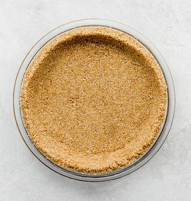 An overhead photo of a pie plate filled with a graham cracker crust recipe.