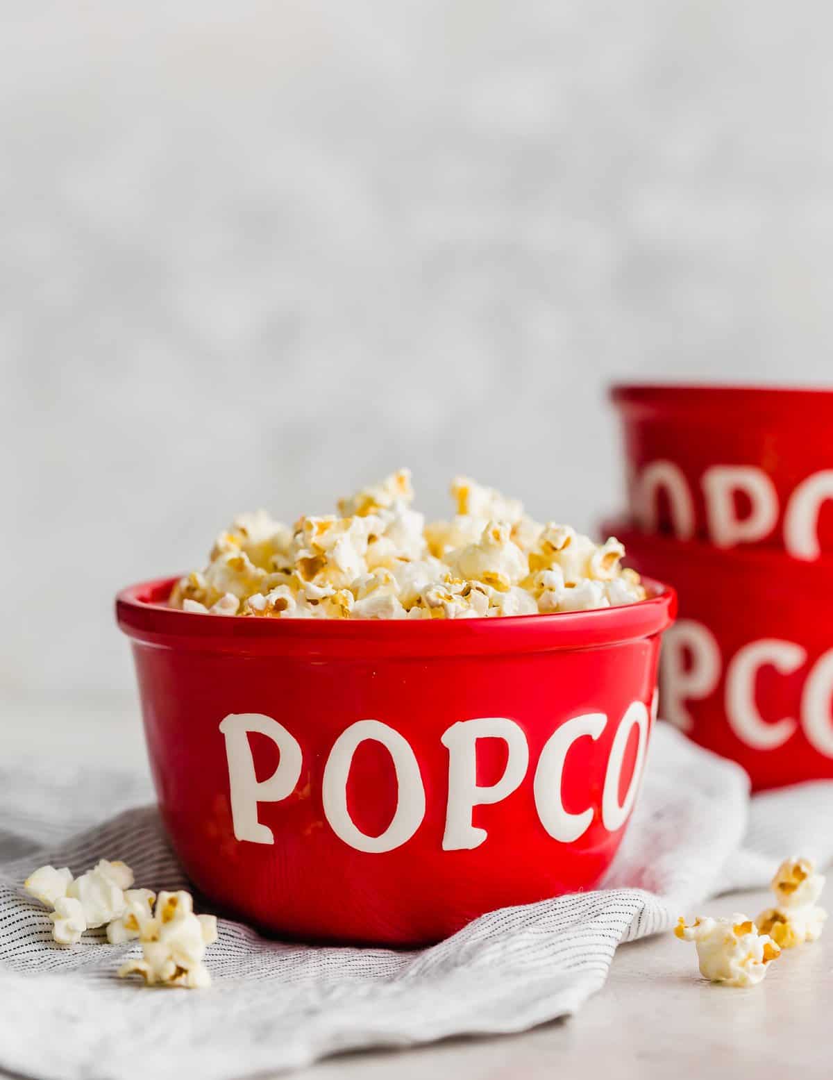 A red bowl with the word "popcorn" on it, with Movie Theater Popcorn inside the bowl.