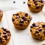 Chocolate chip topped Pumpkin Baked Oatmeal Cups sitting on an open book.