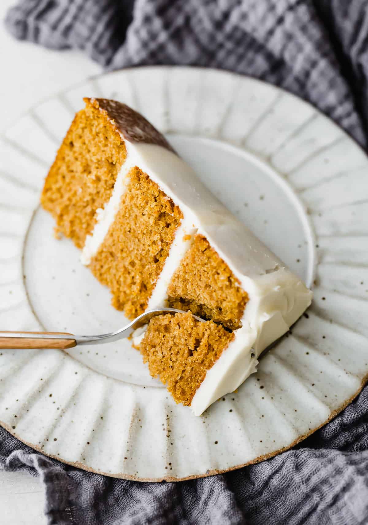 A fork cutting into a slice of Pumpkin Cake on a plate.