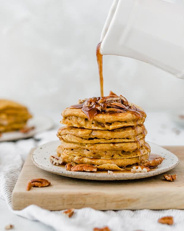 Stack of pumpkin pancakes and syrup drizzled overtop.