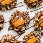 An overhead photo of turtle cookies, a chocolate cookie base rolled in pecans and then topped with caramel and chocolate.