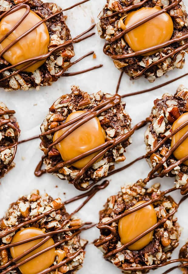 An overhead photo of turtle cookies, a chocolate cookie base rolled in pecans and then topped with caramel and chocolate.
