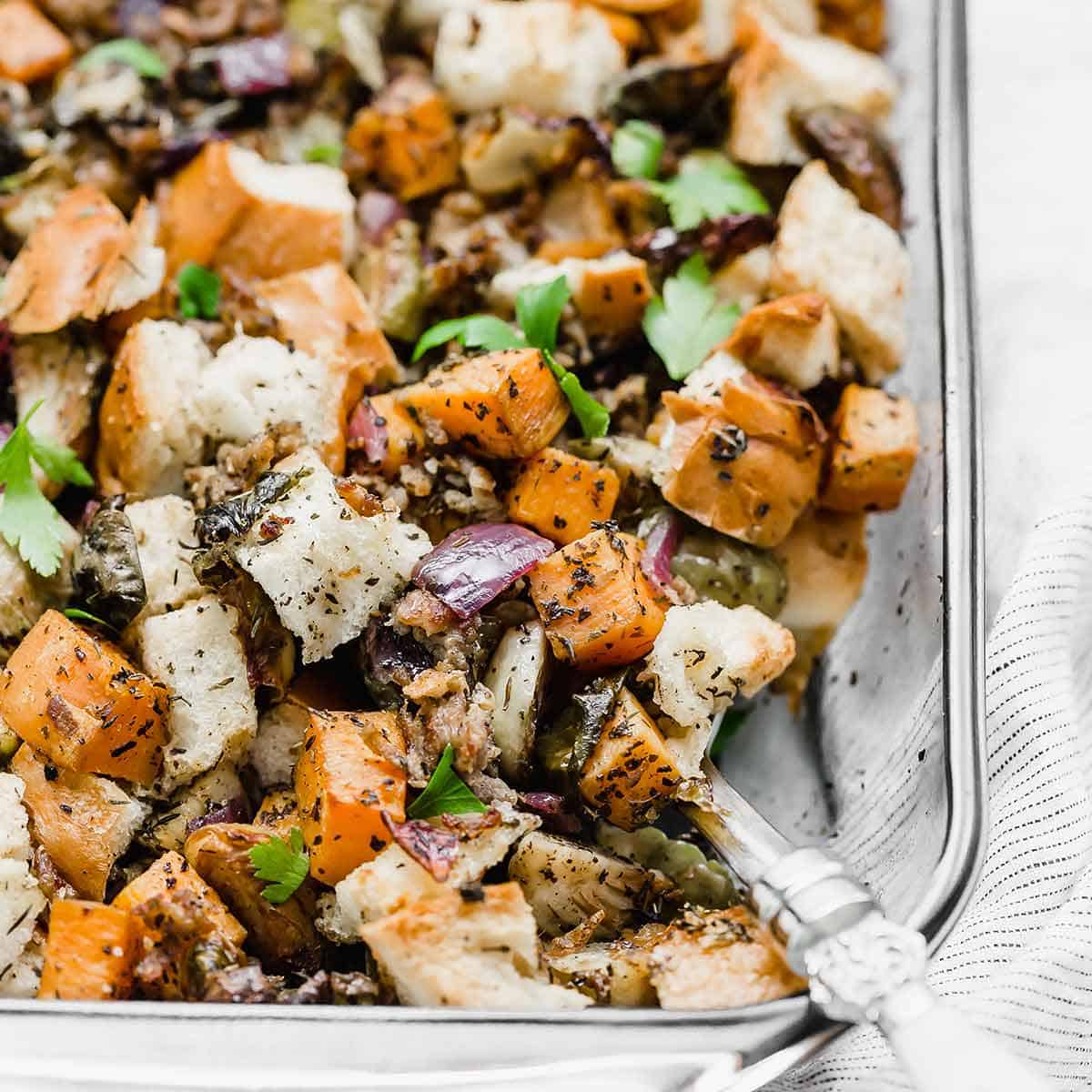 Vegetable Stuffing in a glass baking dish, featuring purple onion, sweet potato, and Brussels sprouts.