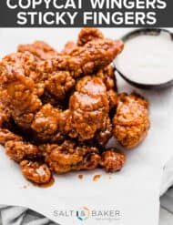 A plate of wingers sticky fingers with ranch in the background.