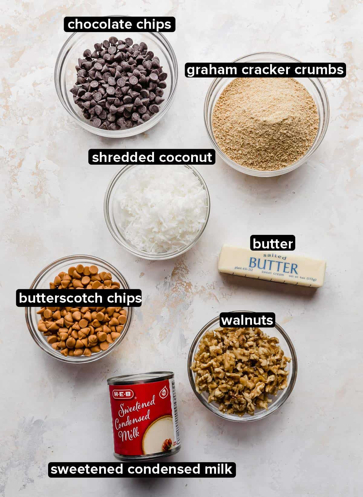 7 Layer Bars ingredients on a white textured background.