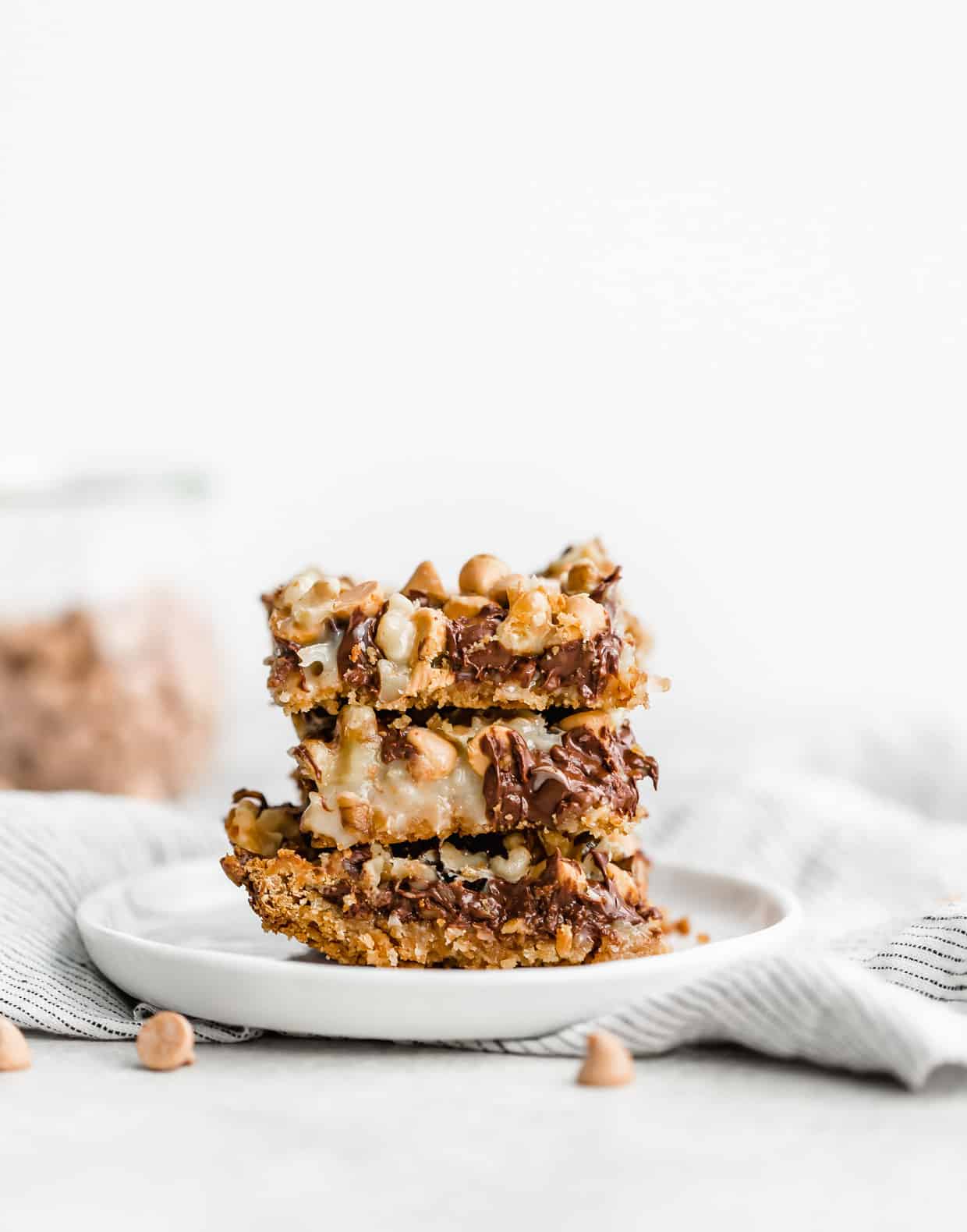 A stack of three 7 Layer Bars on top of each other on a white plate.