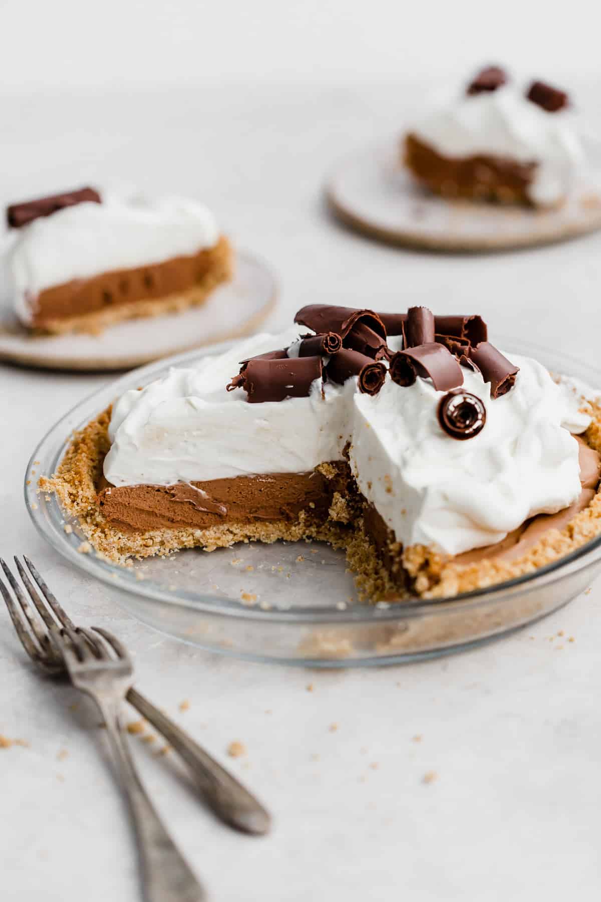 A French Silk Pie on graham cracker crust topped with whipped cream and large chocolate curls.