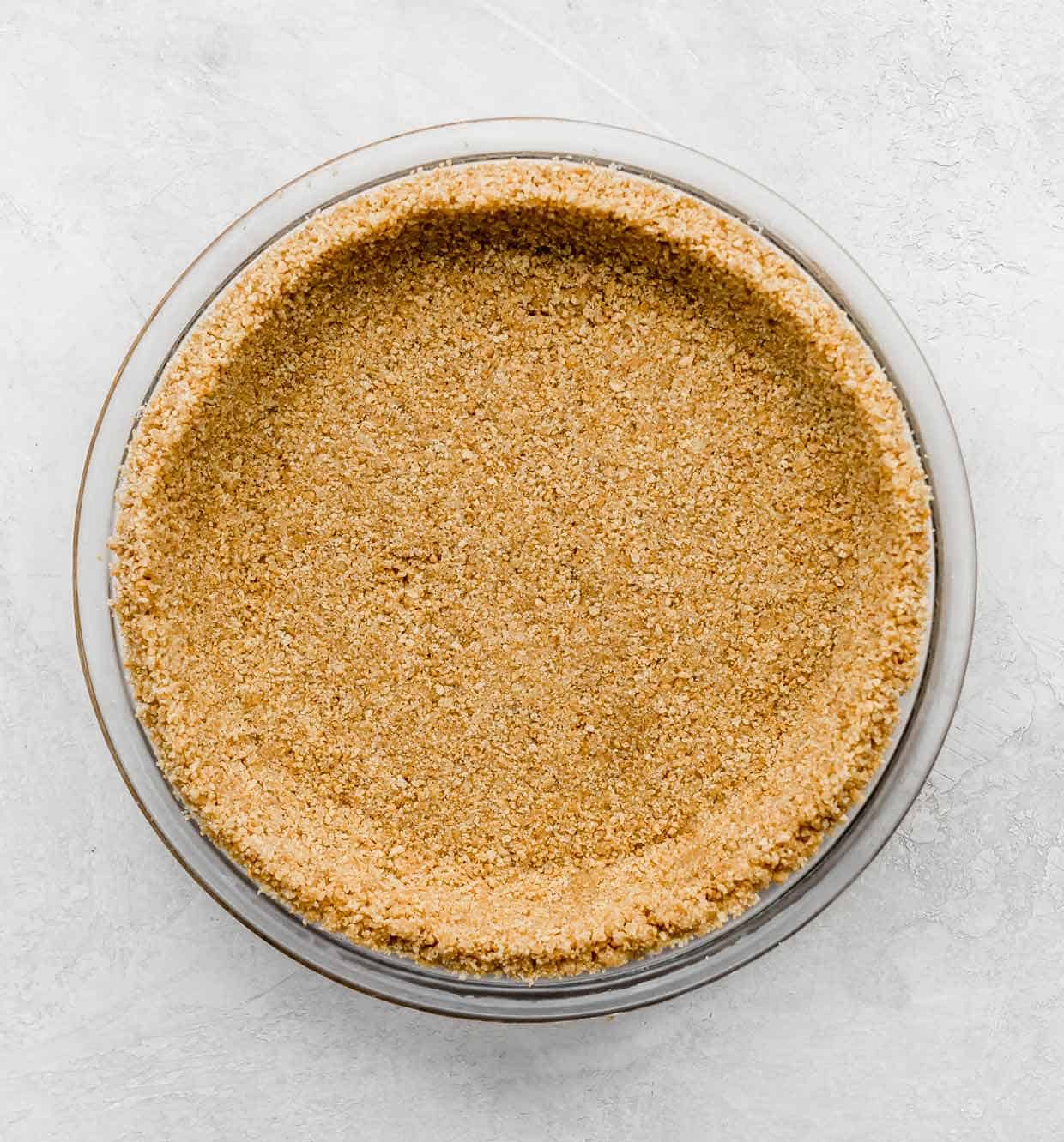 A Graham Cracker Crust in a 9 inch glass pie plate on a light gray background.