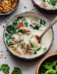 A black bowl with copycat Olive Garden Zuppa Toscana Soup in it and a spoon.
