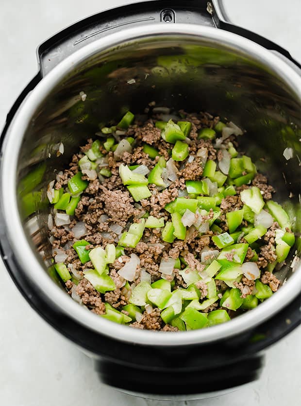 Ground beef, onions, and green peppers in an Instant Pot.