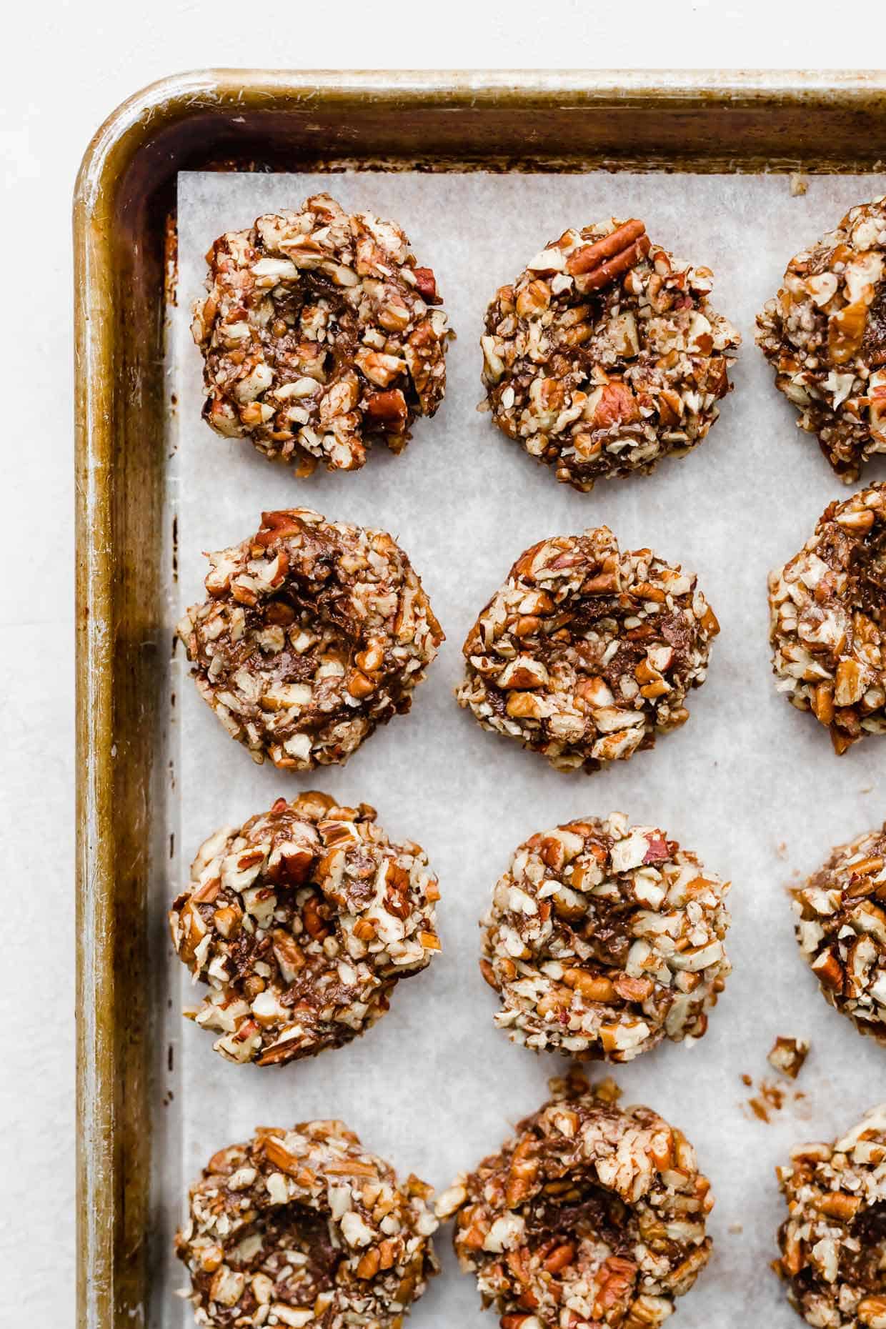 Pecan covered chocolate cookie dough balls with a thumbprint indentation in the center of each ball.