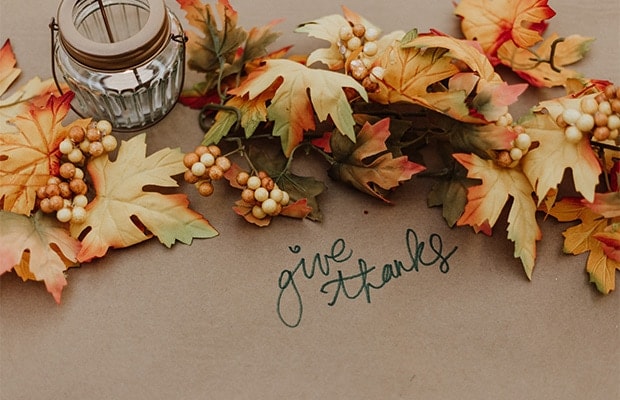 Leaves on a table with "give thanks"written on the tablecloth.