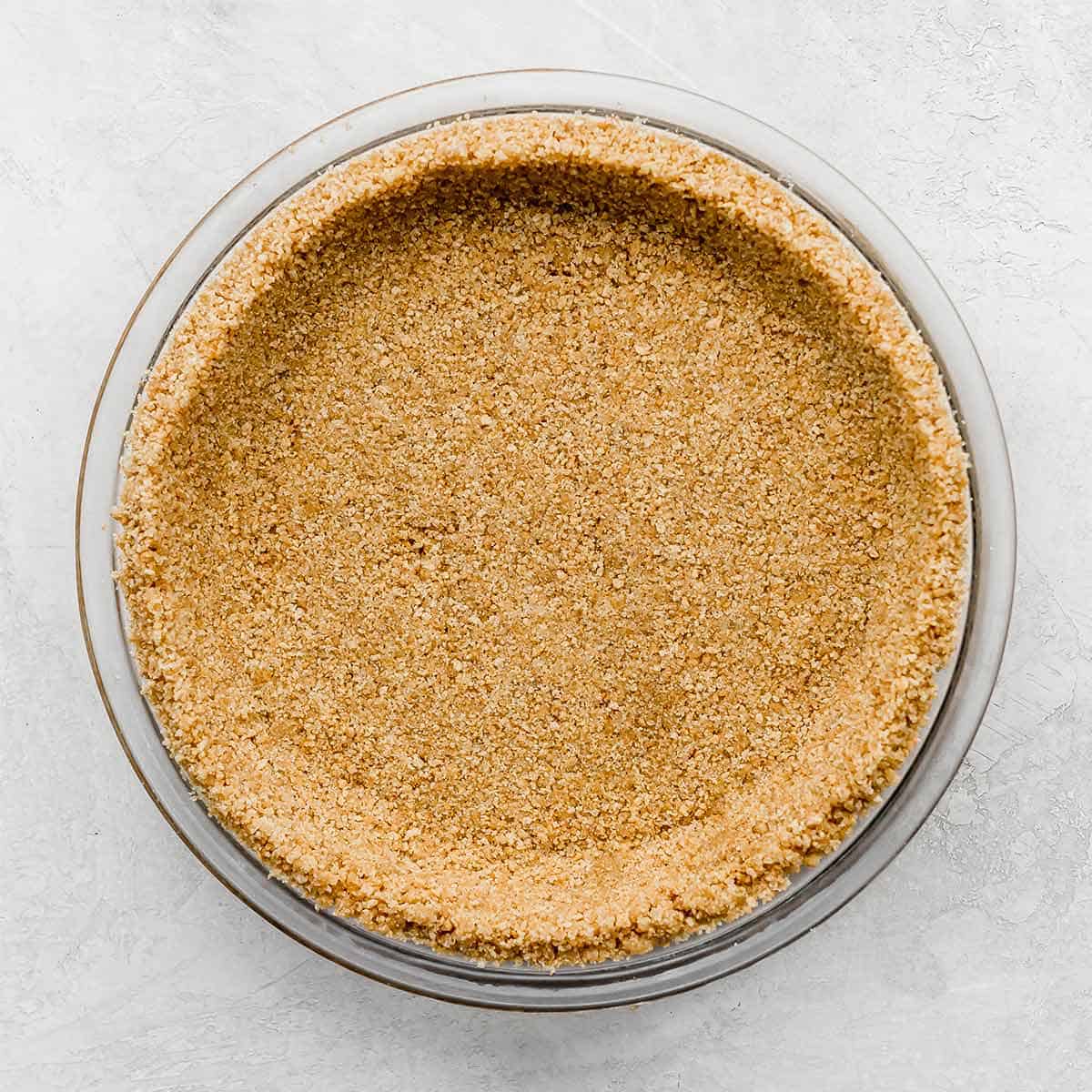 A homemade Graham Cracker Crust pressed into a pie plate on a light gray background.