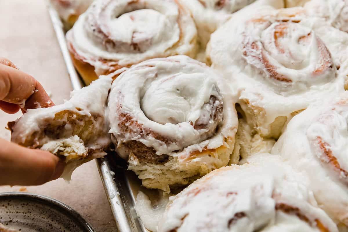 A hand pulling a spiral of cinnamon roll.