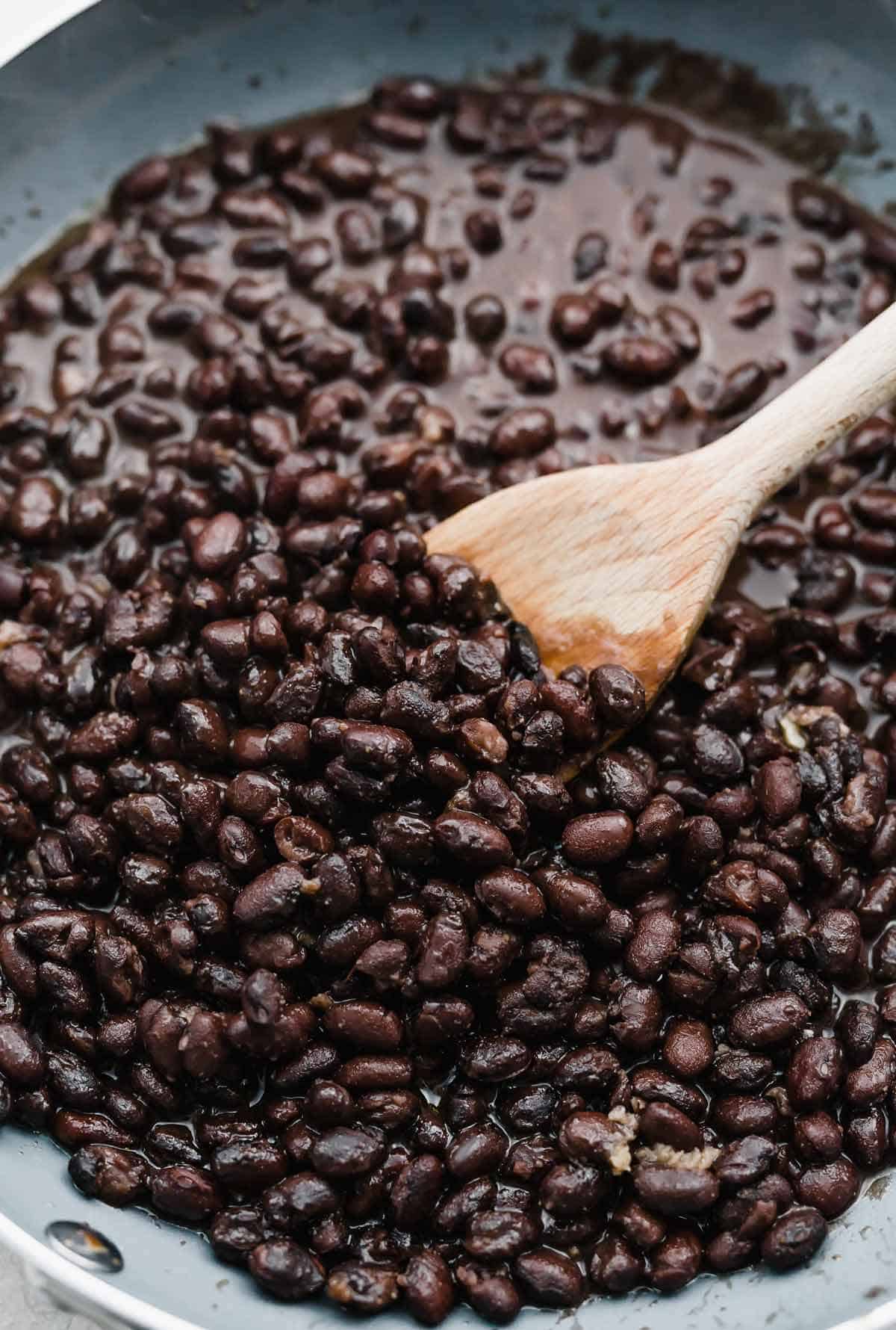 Canned black beans cooked in a gray skillet.