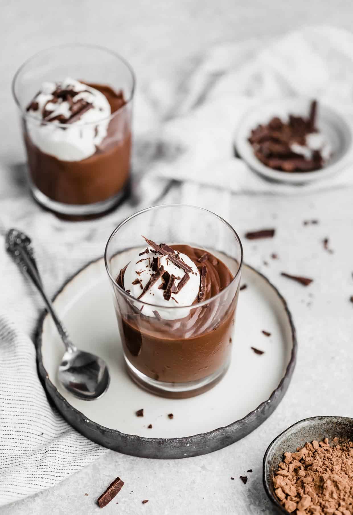 Homemade Chocolate Pudding in a glass cup topped with whipped cream and chocolate shavings.