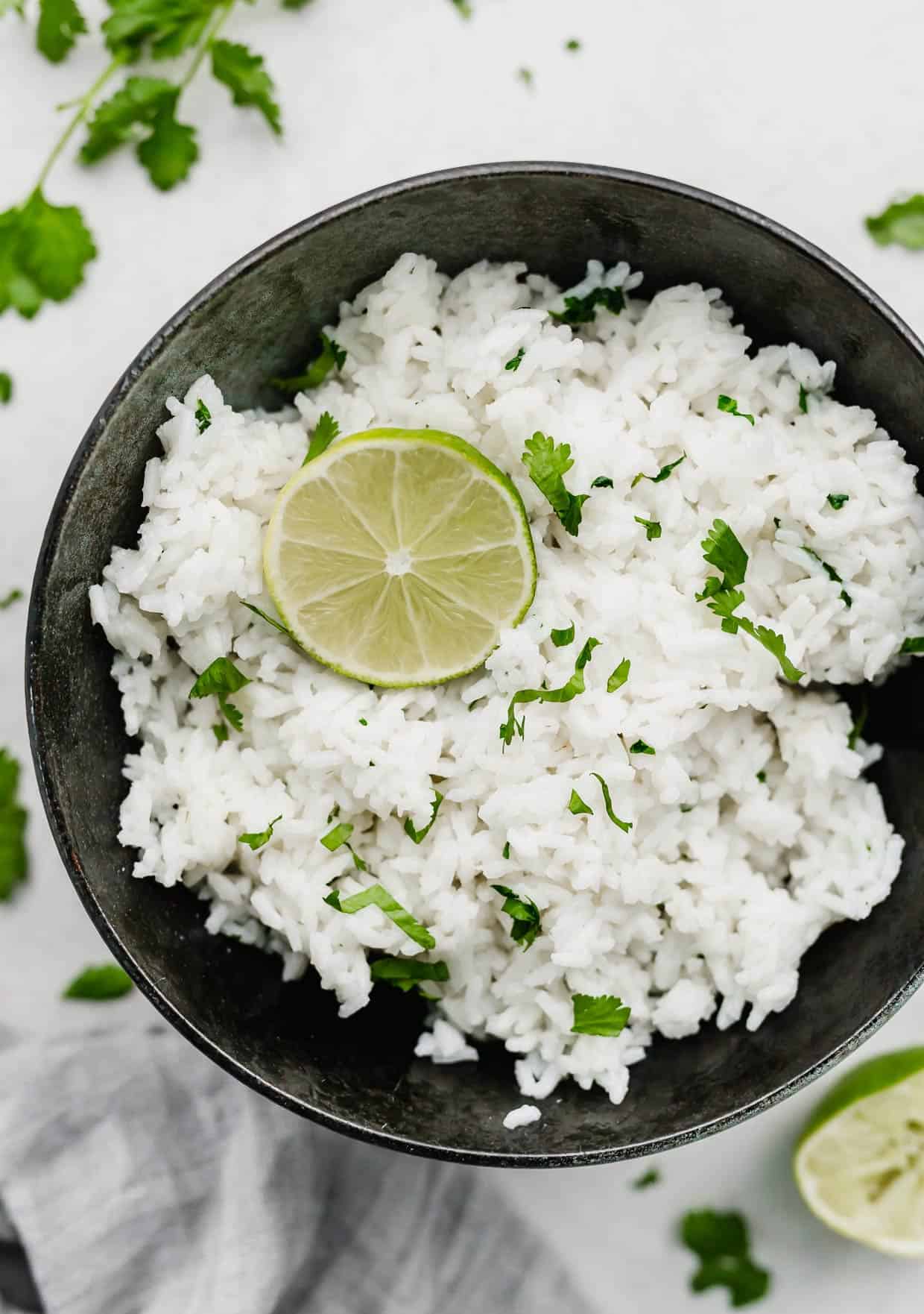 A black bowl with Cilantro Lime Rice in it that's topped with a circle lime slice.