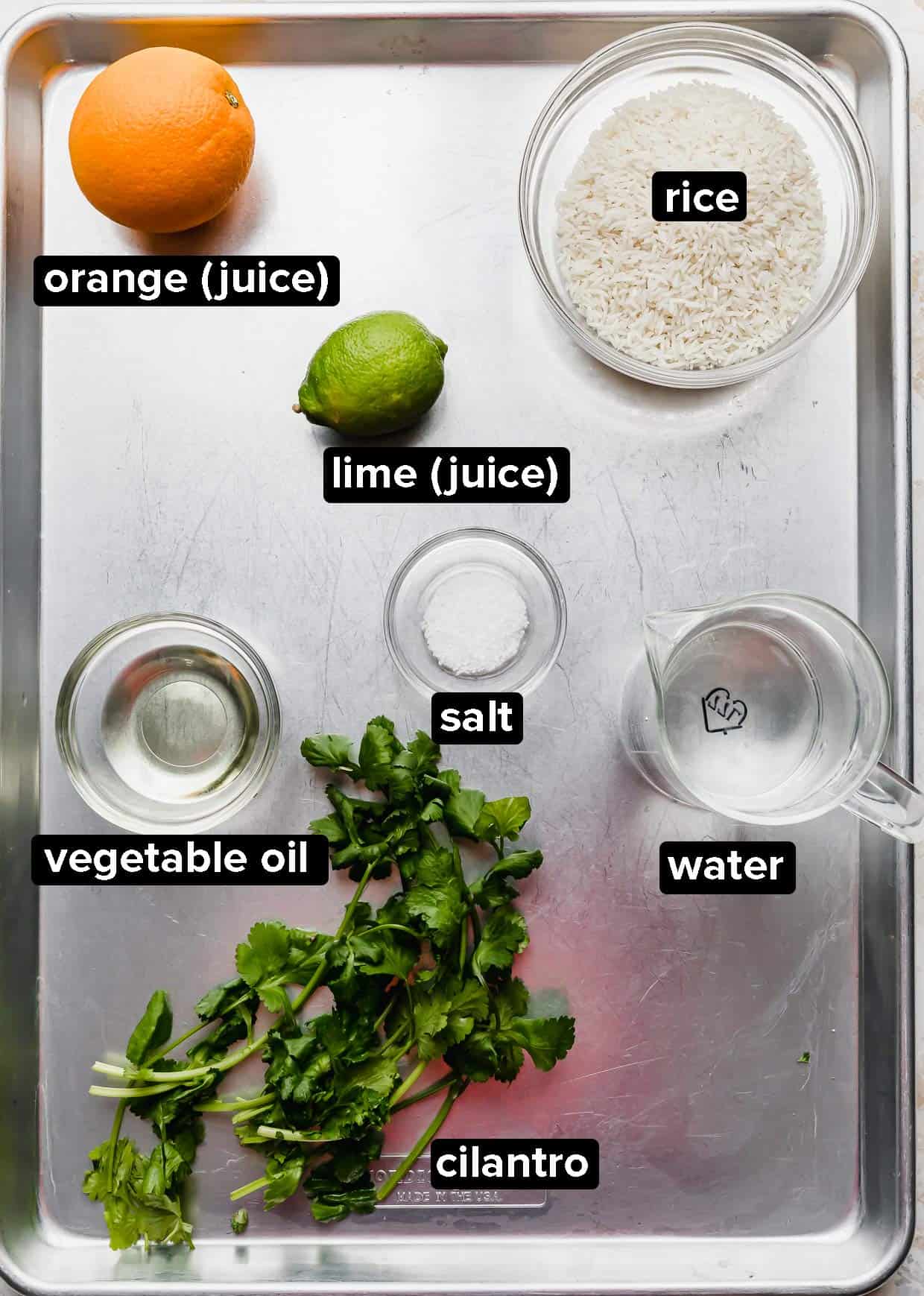 Cilantro Lime Rice ingredients portioned into glass bowls on a silver baking sheet.