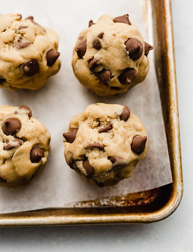 A large ball of chocolate chip cookie dough on a baking sheet.
