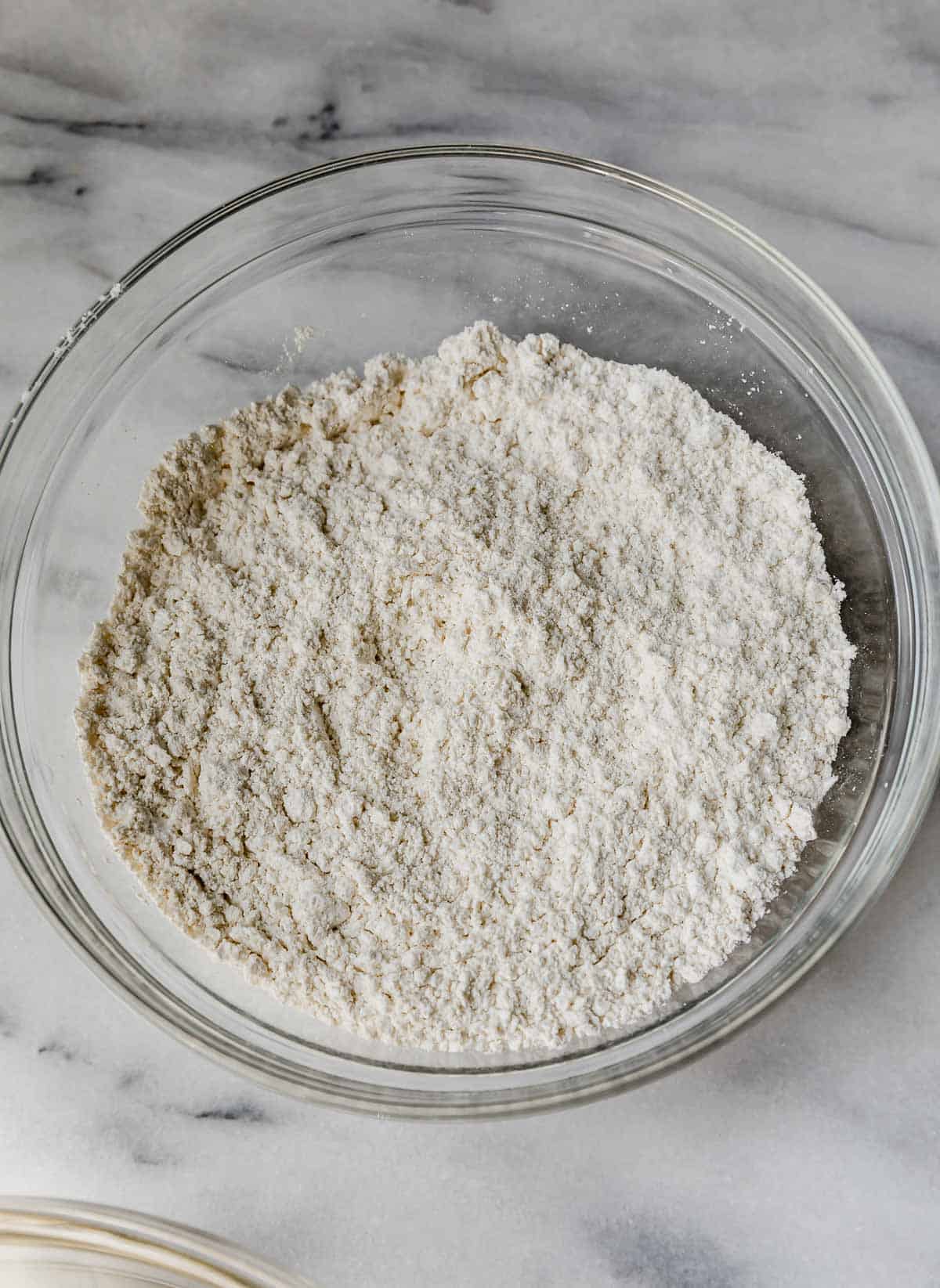 Dry ingredients in a glass bowl on a marble background.