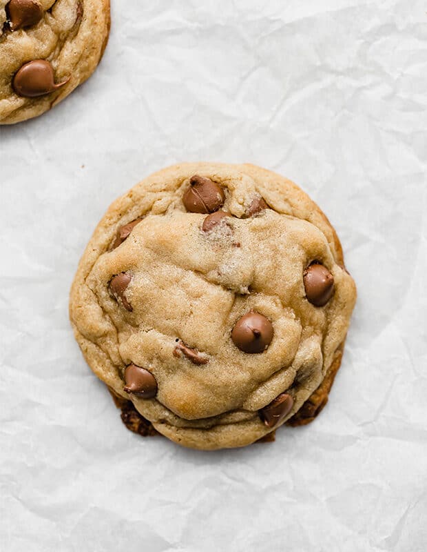 A copycat Crumbl chocolate chip cookie on a white parchment paper. 