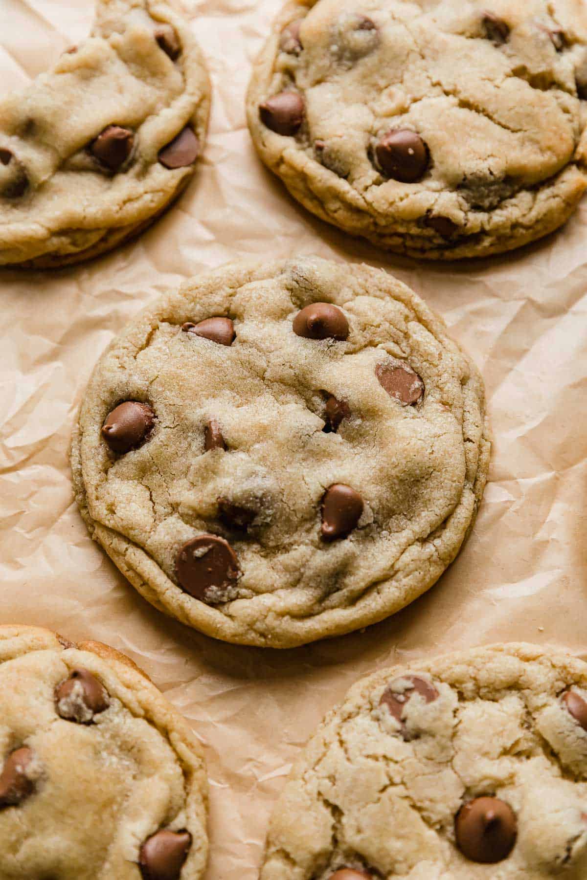 A Crumbl Chocolate Chip Cookie on a tan colored parchment paper.