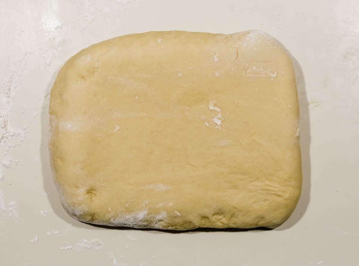 A rectangle of brioche bread dough on a white countertop.