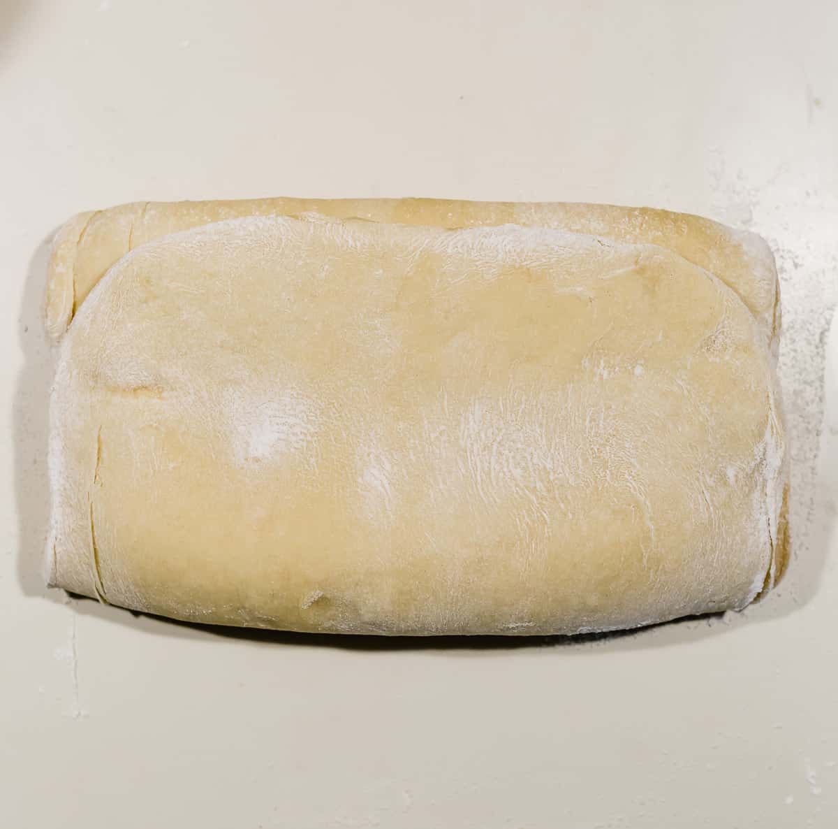 A rectangle of Flaky Brioche Bread dough on a white counter top.