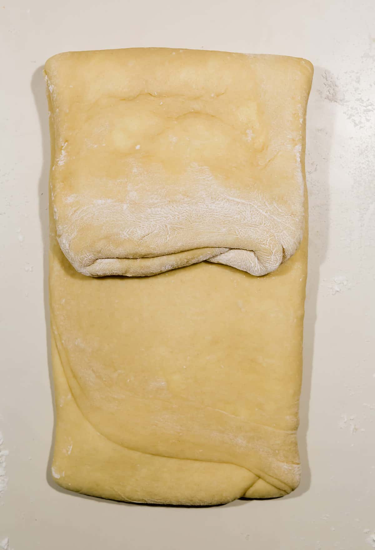 Laminating brioche bread, the top half of the brioche dough folded over onto itself. 