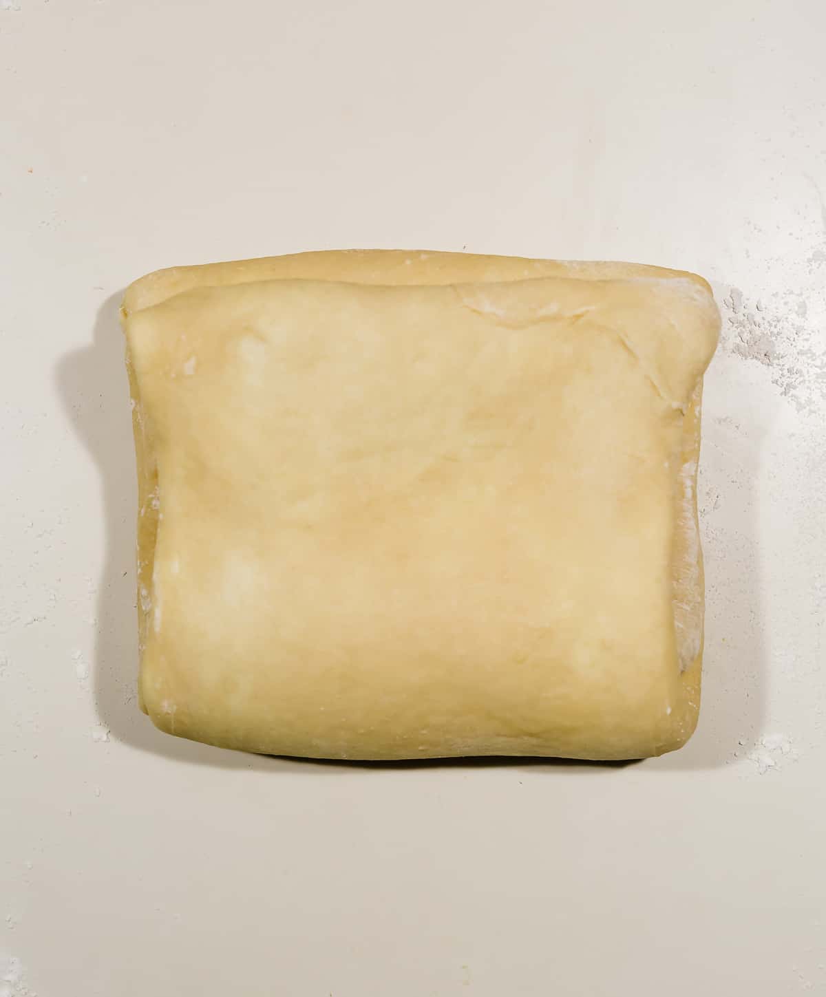 A square of flaky brioche bread dough on a white countertop. 