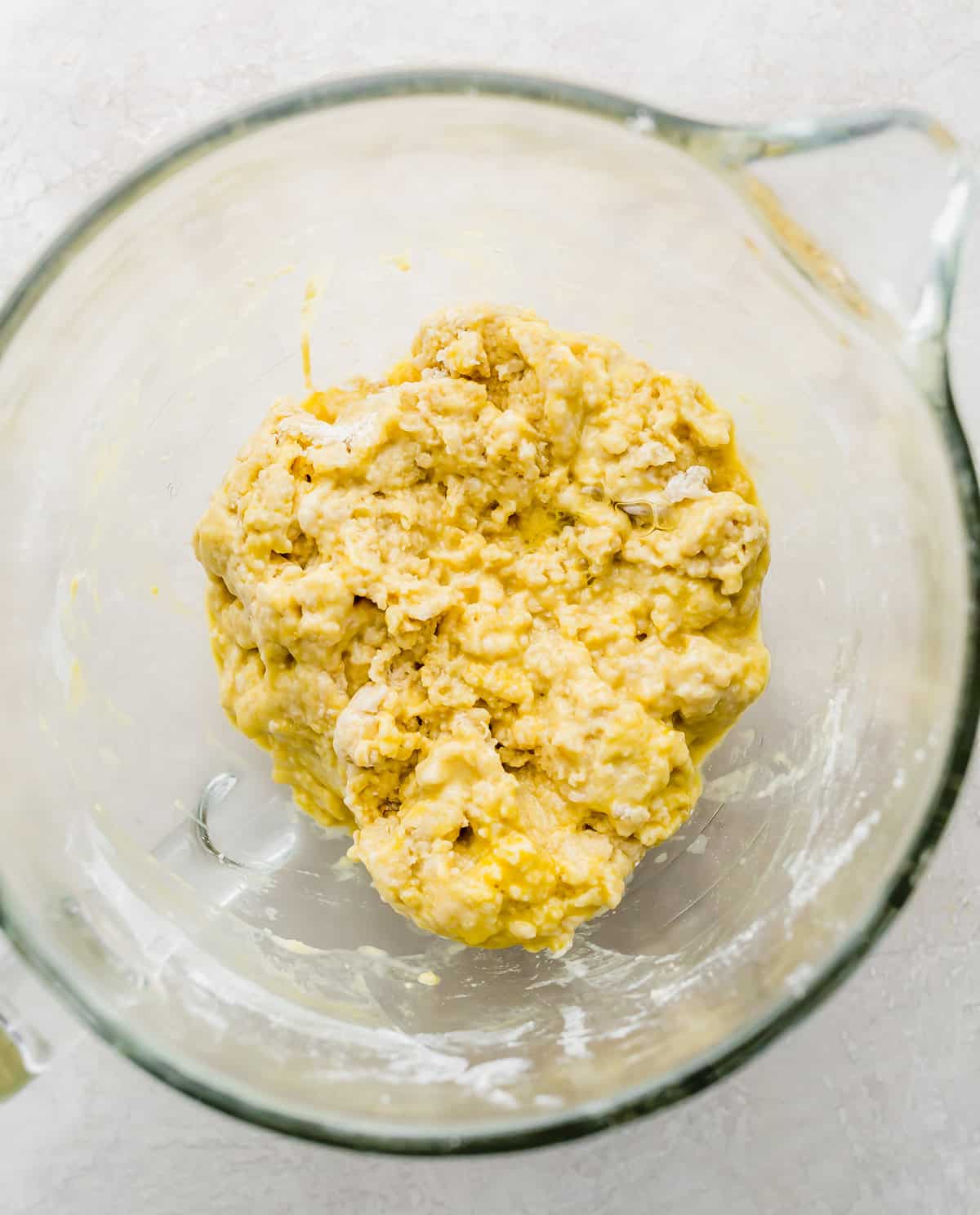 A glass bowl with lumpy Brioche Bread dough in it.