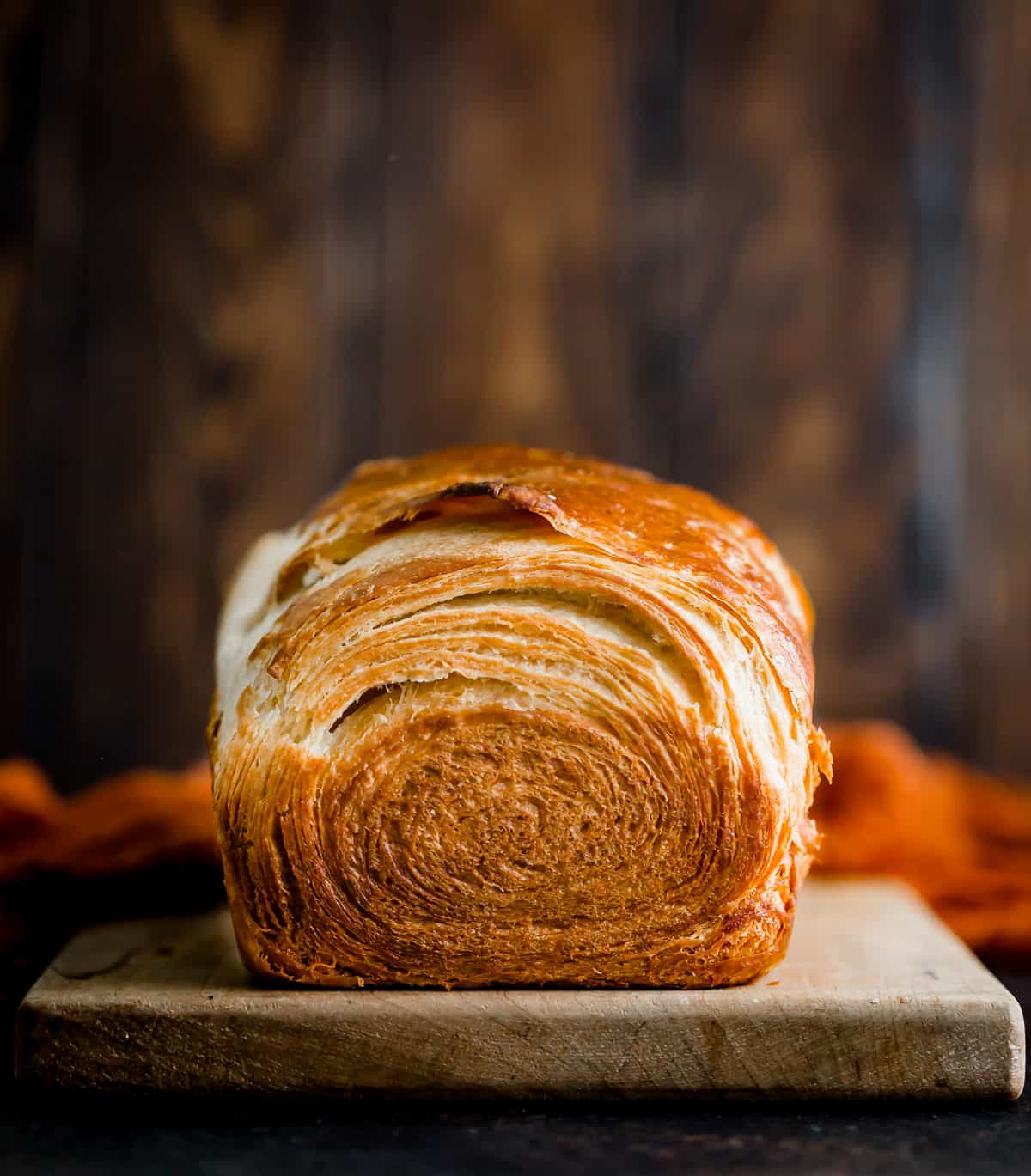 Flaky Brioche Bread against a dark Woden background. 