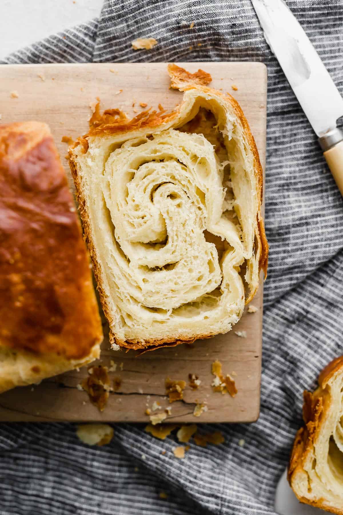 A slice of flaky bread on a wooden cutting board.