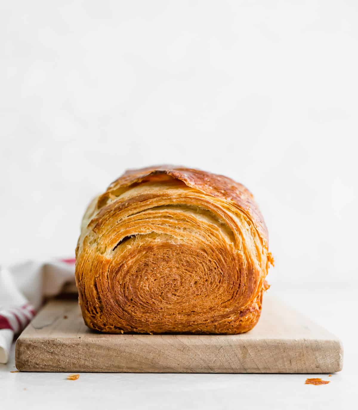 Flaky Brioche Bread on a wooden cutting board against a white background.