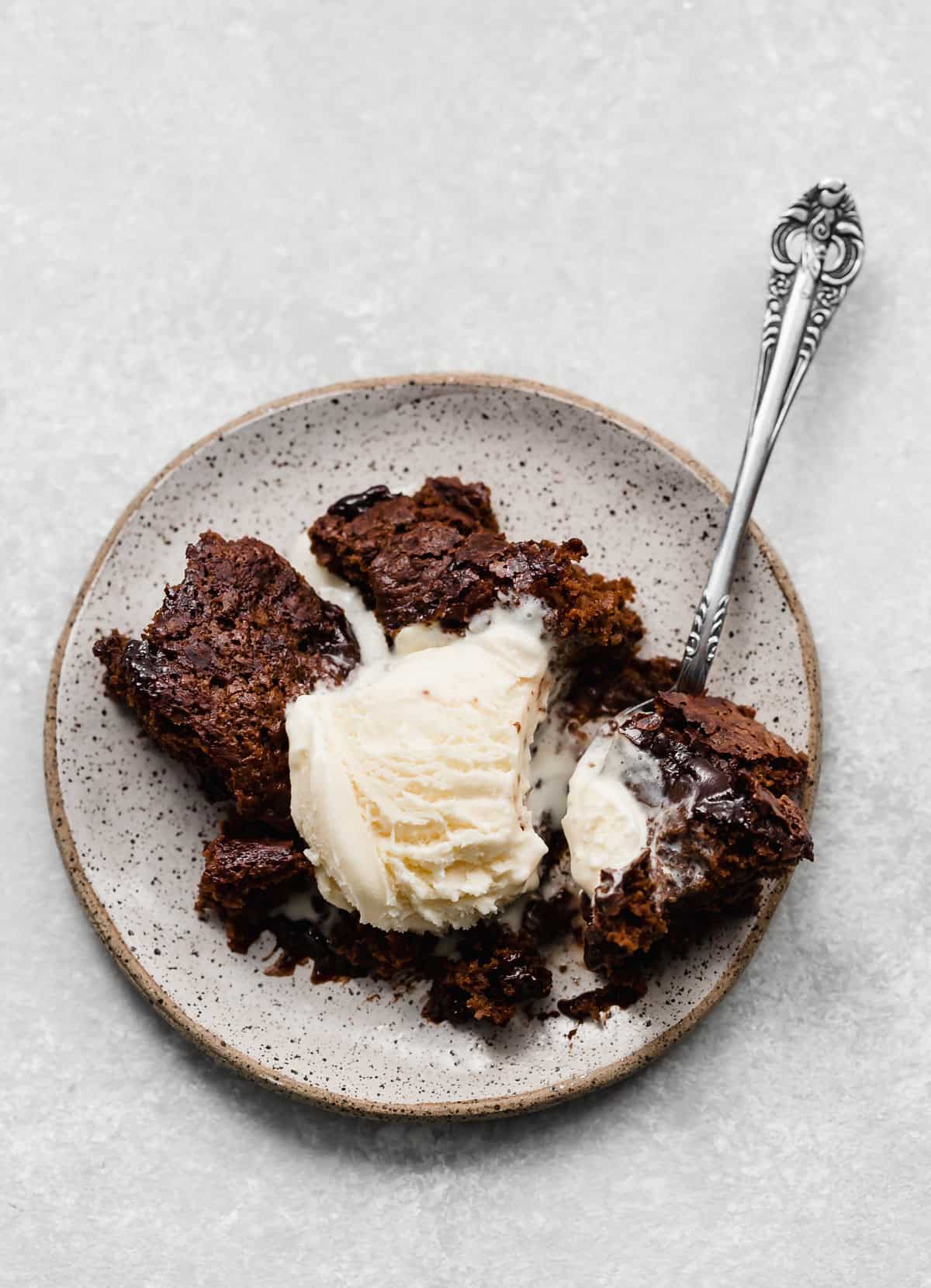 Overhead photo of hot fudge cake on a plate topped with a scoop of vanilla ice cream.