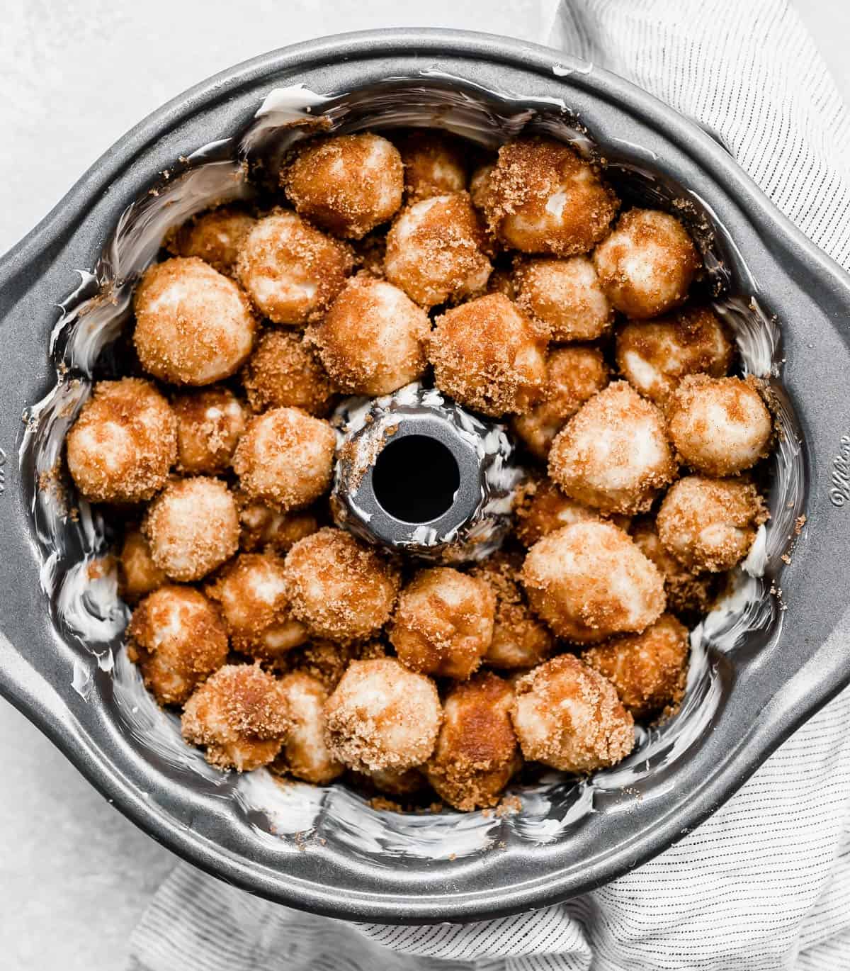 A bundt pan with cinnamon sugar coated dough balls for making The Best Monkey Bread Recipe.