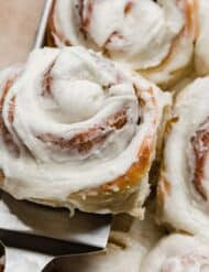 A close up of a vanilla frosting cinnamon roll.