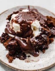 Hot fudge cake on a plate topped with ice cream and hot fudge sauce.